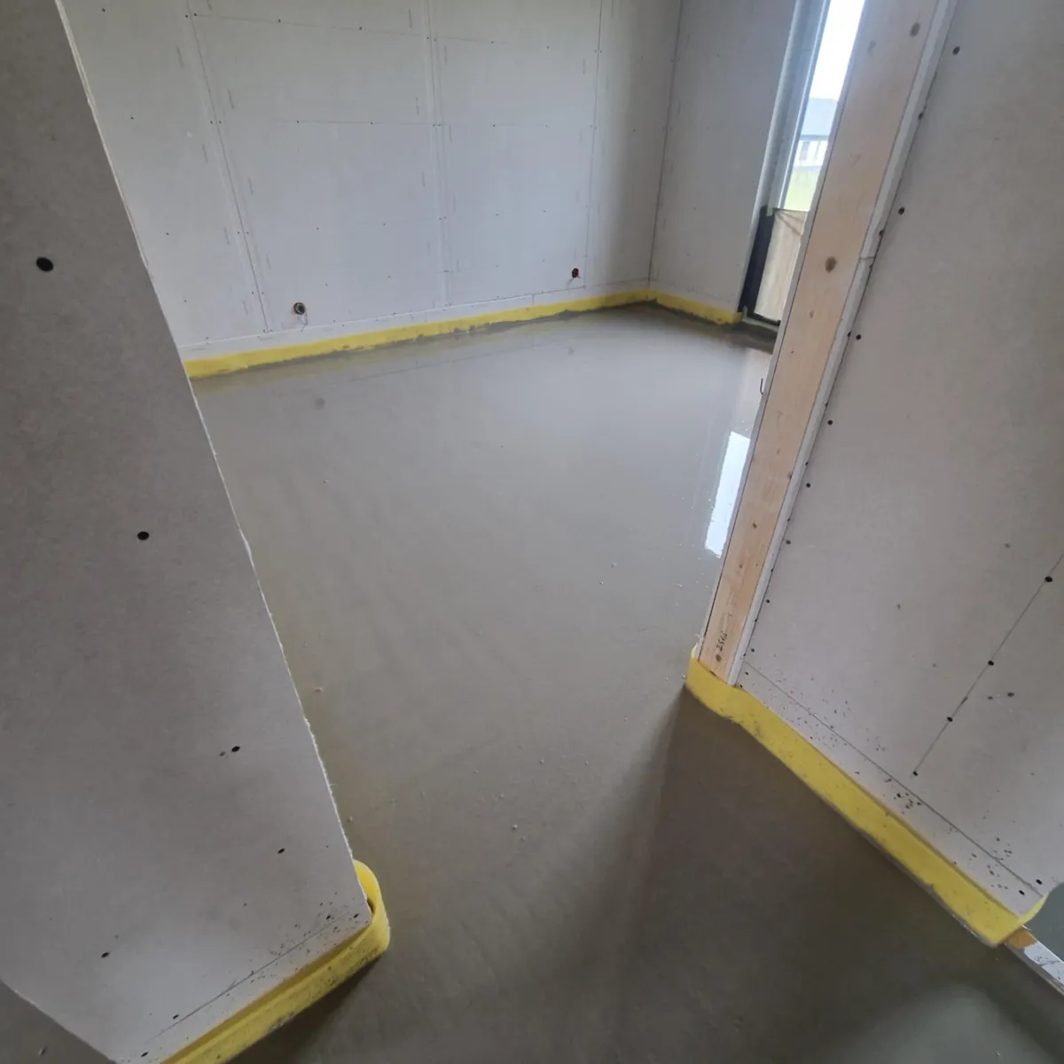 Pomieszczenie z świeżą, równomiernie rozlaną wylewką anhydrytową na podłodze, gotowe pod ogrzewanie podłogowe