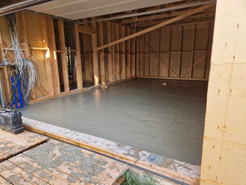 Wylewka anhydrytowa w pomieszczeniu z odsłoniętymi stelażami ściennymi i świeżo wygładzoną powierzchnią podłogi