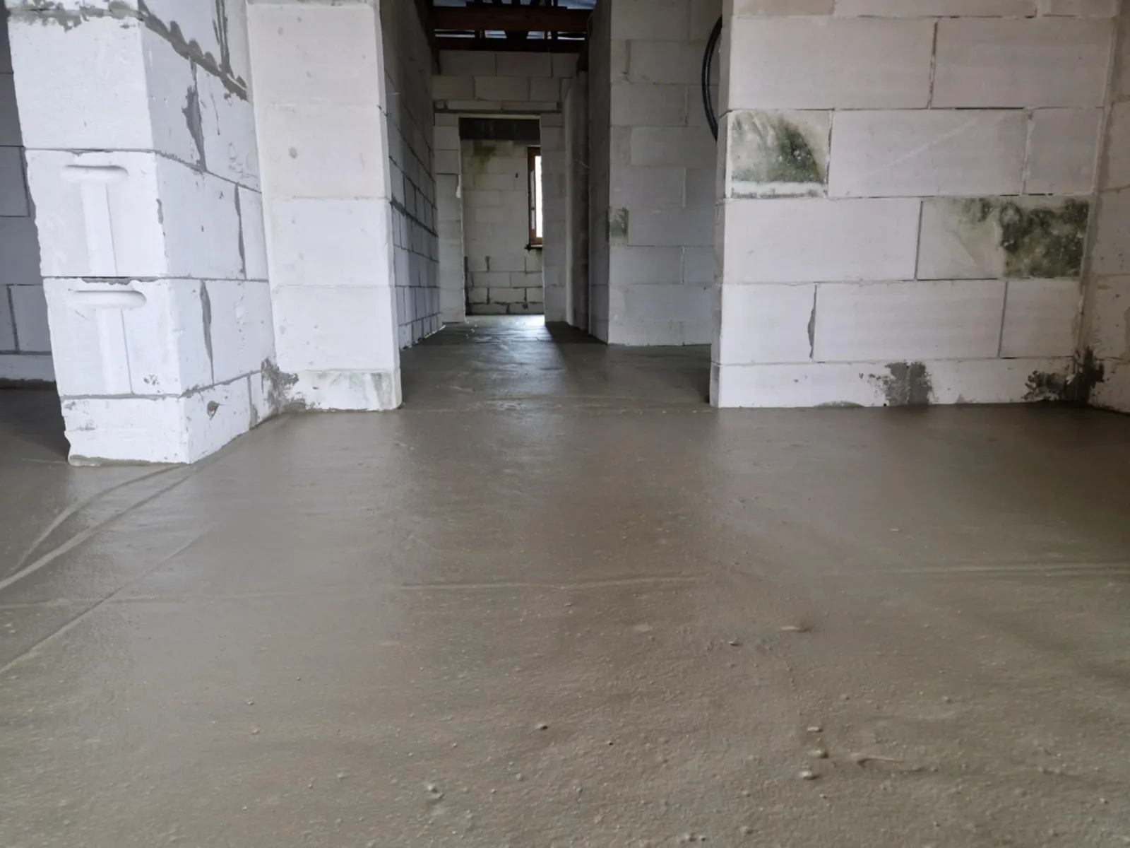 Wnętrze budynku z równą, świeżą wylewką anhydrytową na betonowym podłożu i ścianami z bloczków gazobetonu