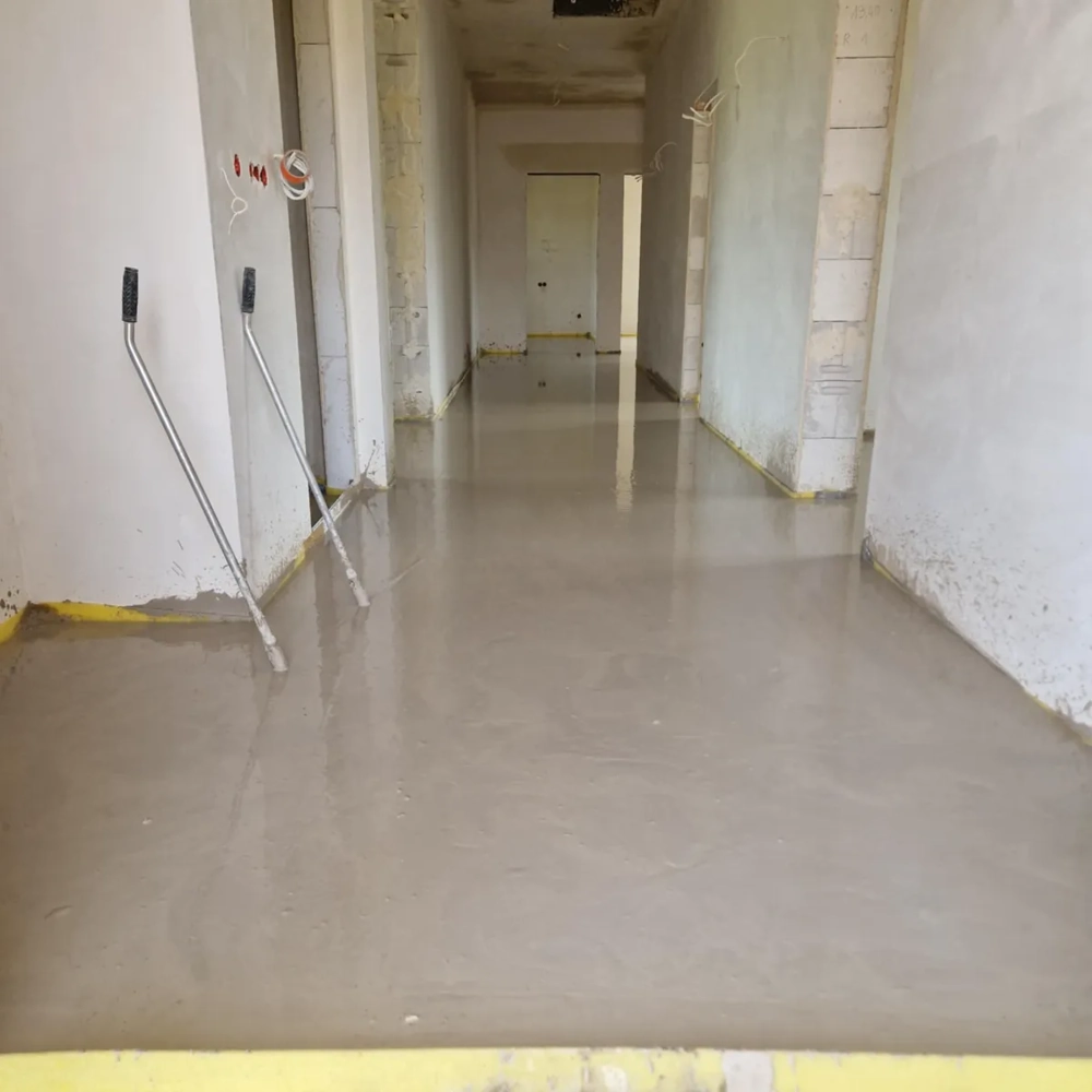 Świeżo wykonana wylewka anhydrytowa w korytarzu z narzędziami wyrównującymi