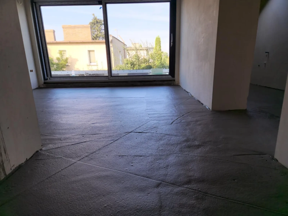 Wylewka anhydrytowa równomiernie rozprowadzona na surowej posadzce w salonie z dużym oknem tarasowym